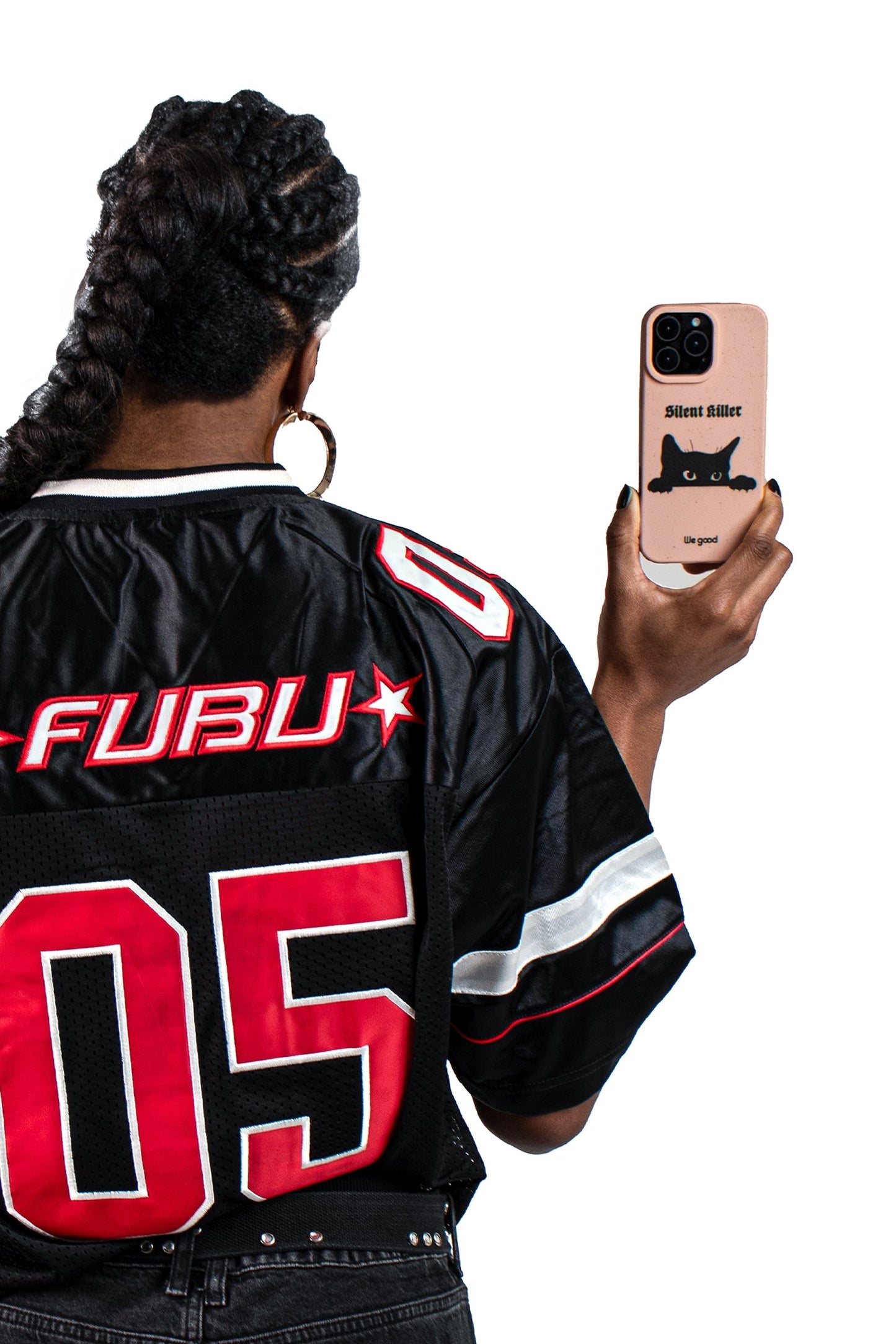 Woman with a black and red jersey holding a We Good Tpu iPhone case with wheat mix speckled in a flamingo pink color with a black 'silent killer' text in a gothic font and below it a black cats face creeping up and stalking.