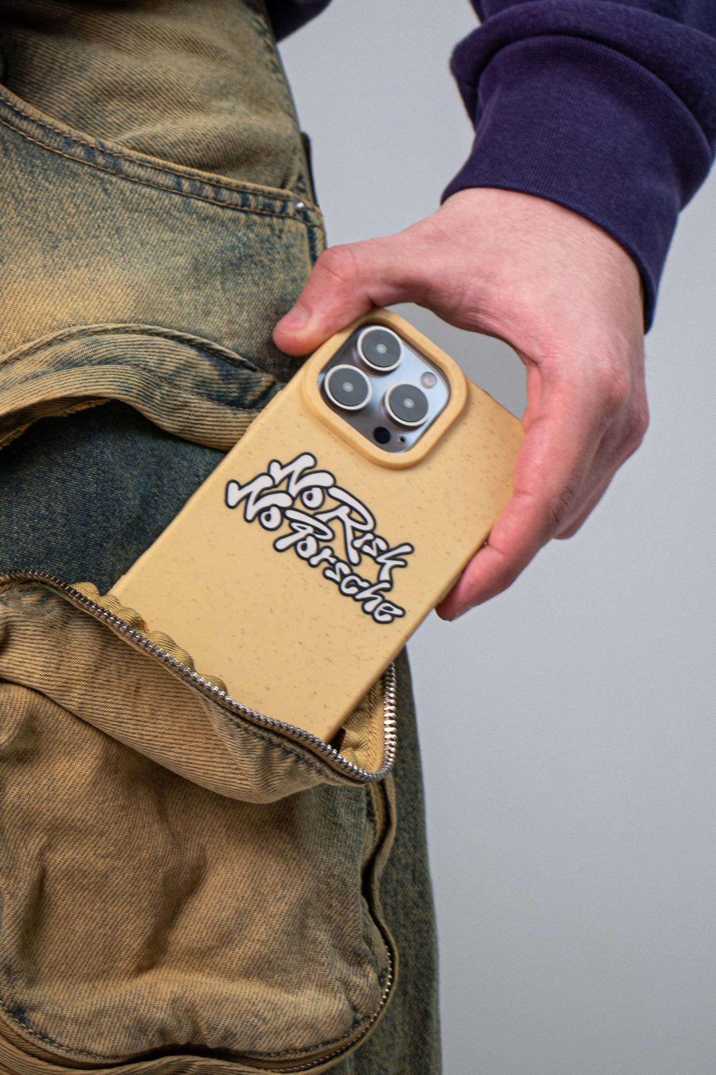 Man wearing vintage denim jeans pulling a We Good Tpu iPhone case with wheat mix speckled in a canary yellow color with black "No Risk No Porsche" bubble text print out of his pocket.