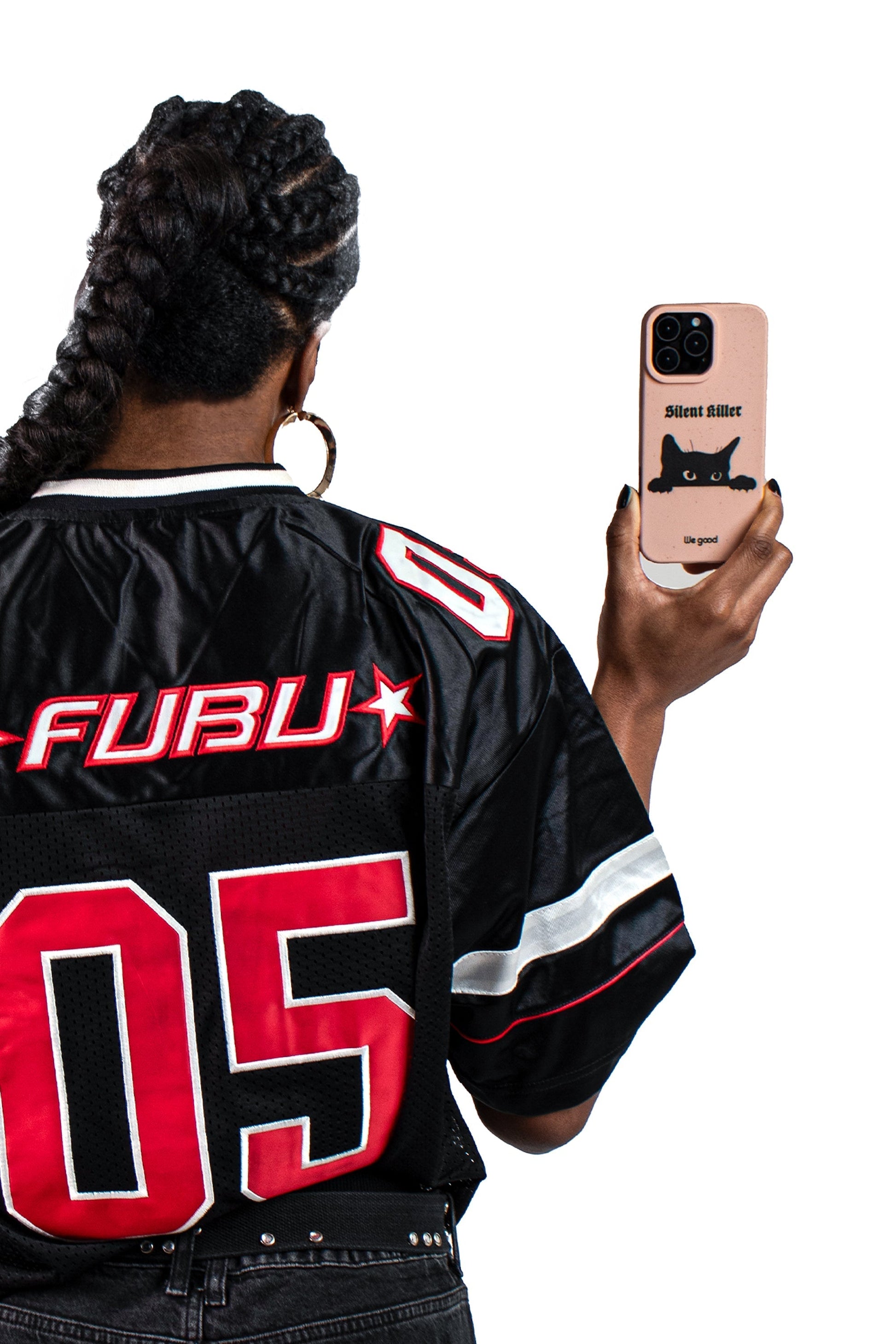 Woman with a black and red jersey holding a We Good Tpu iPhone case with wheat mix speckled in a flamingo pink color with a black 'silent killer' text in a gothic font and below it a black cats face creeping up and stalking. 