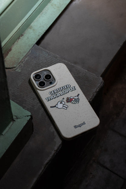 We Good Tpu iPhone case with wheat mix speckled in an off-white color with 'certified trakadoros' white and black bold text print and below it two cartoon hands with white gloves with one holding a red pack of cigarettes and the other hand taking one from the pack resting on the ground in a street setting at night.